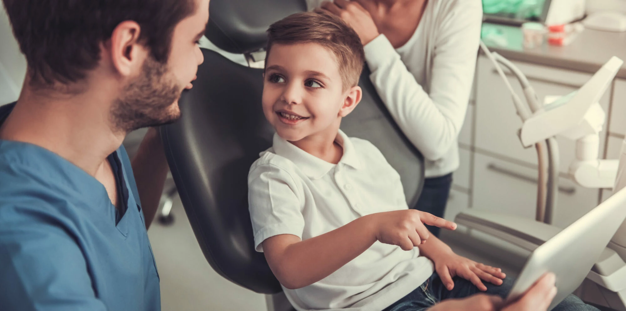 Young patient smiling at the dentist with his parent beside him