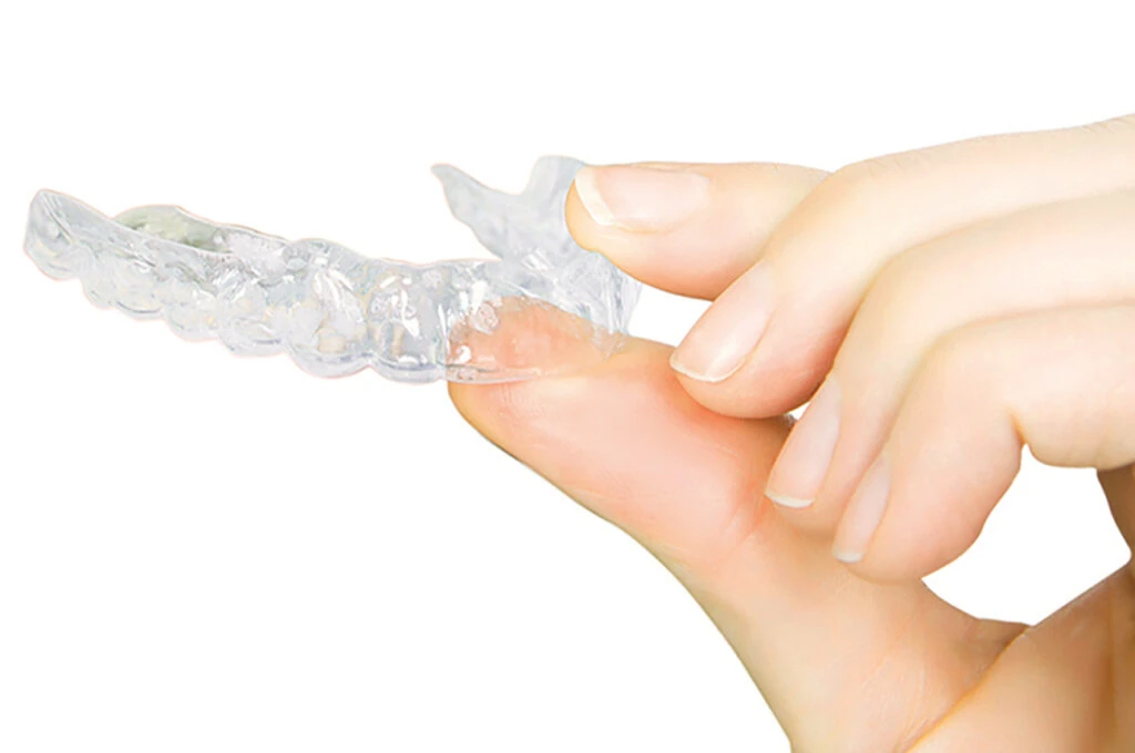 Clear aligner held between fingers